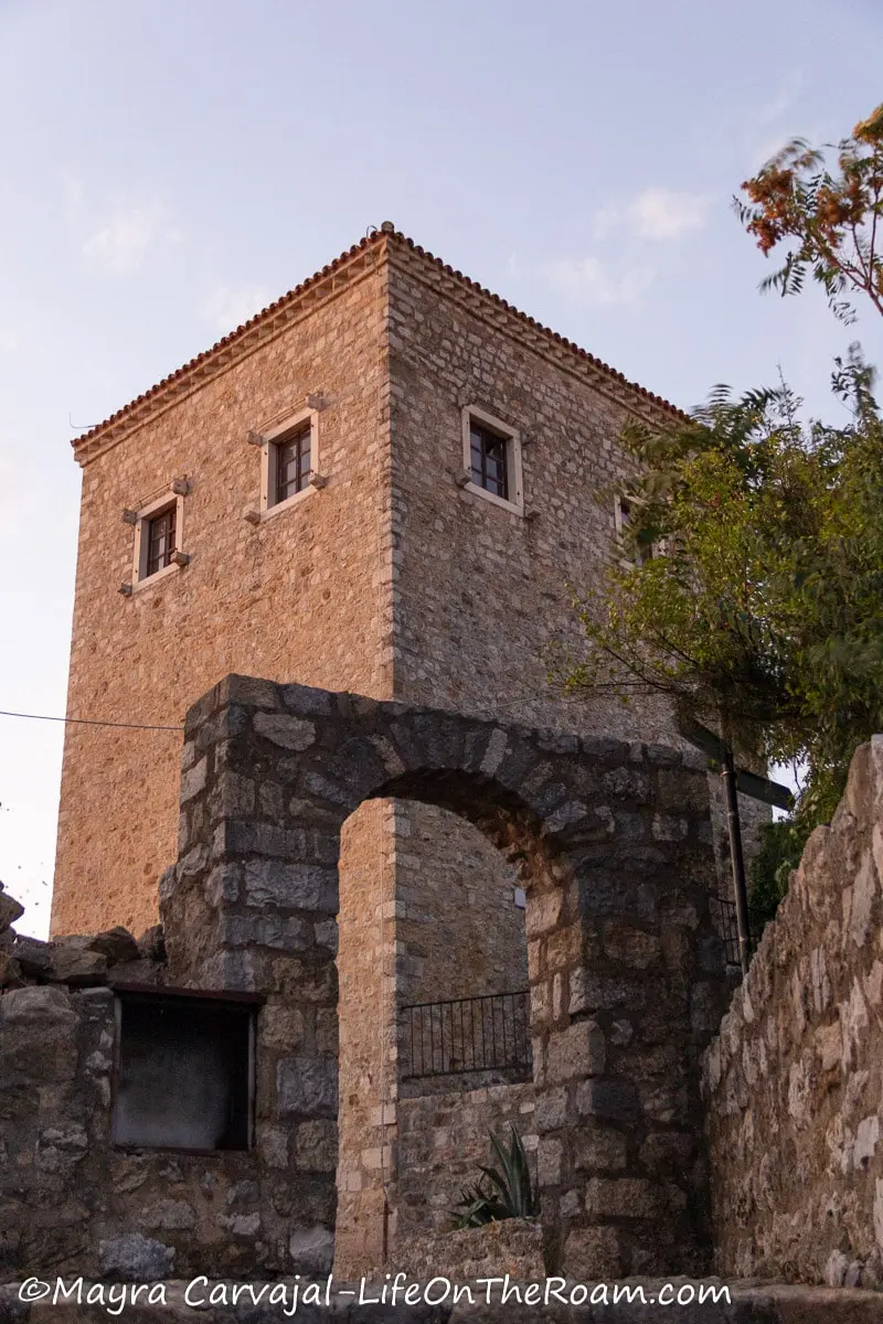 View of a tall rectangular towers with a stone arch in the foreground