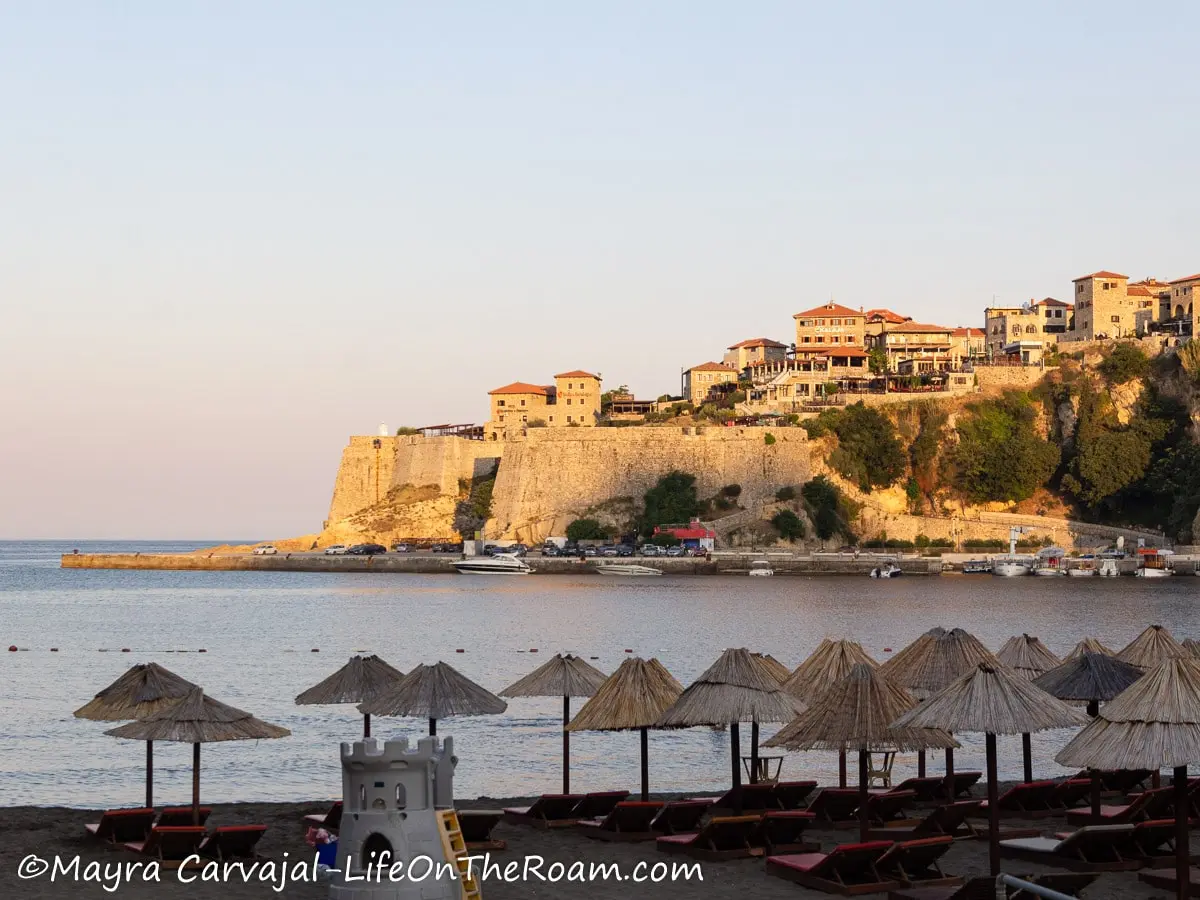 A sandy beach with umbrellas with the view of a fortress