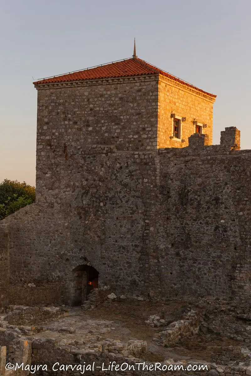 A tall rectangular tower with a hipped roof, attached to a wall. It has a small door at the bottom and two small windows on the side.