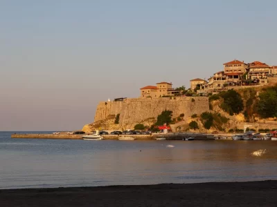 View of an old fortress with stone buildings across a beach on a sunny and calm day