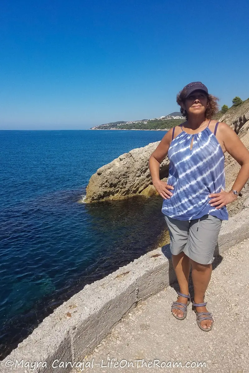 Mayra on a sloped concrete path with the sea in the background