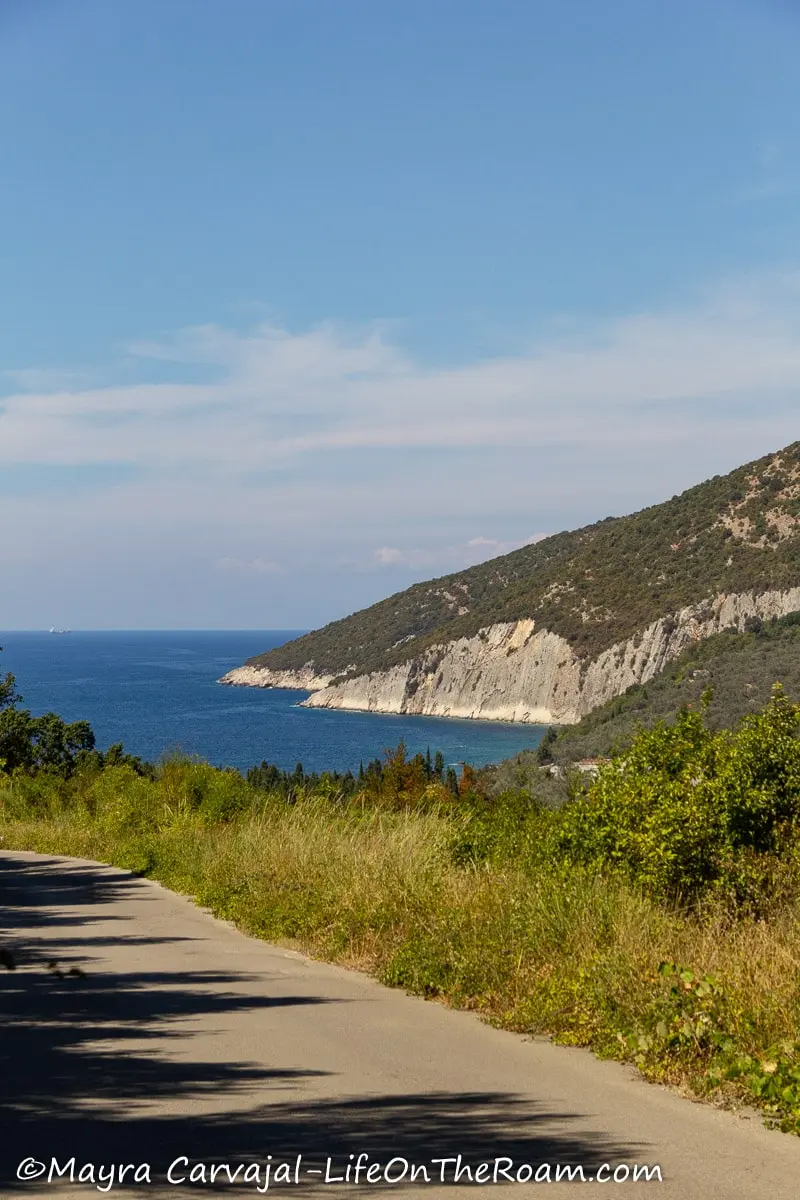 View of a coast with a hill and blue sea from a high road