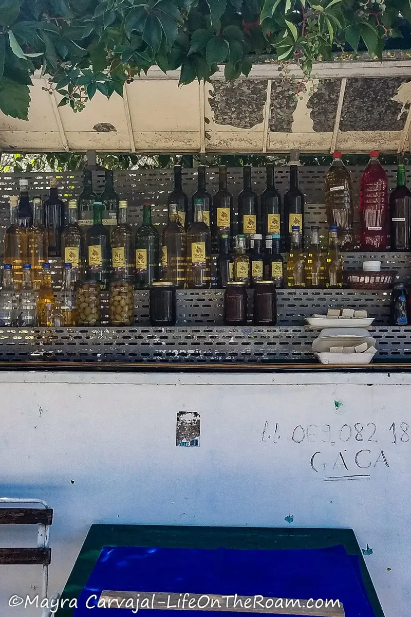 A cart with shelves filled with bottles of olive oil, juices, olives and other food products