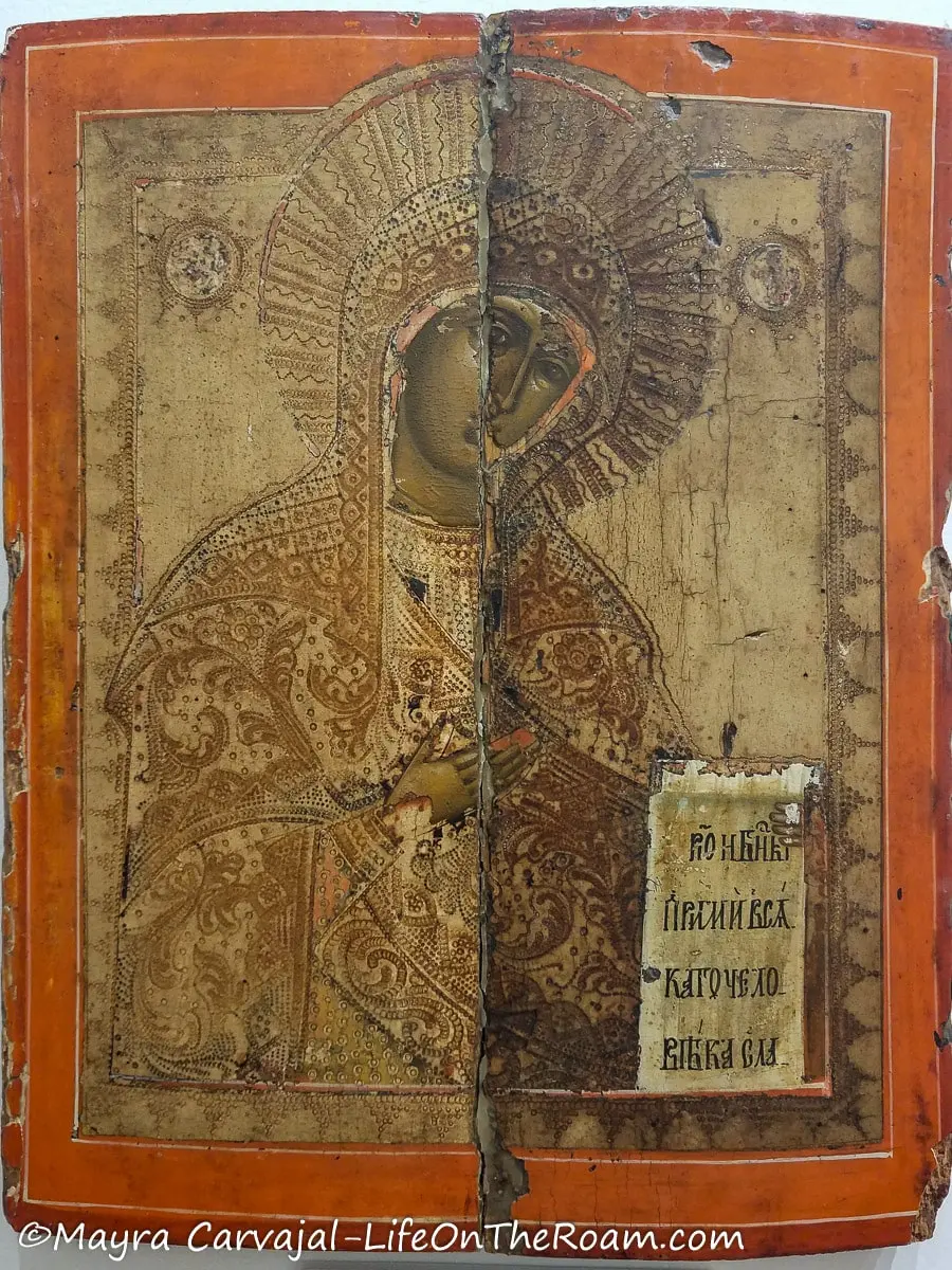 An oil painting of Virgin Mary in Russian school style in muted warm colours and a painted orange frame