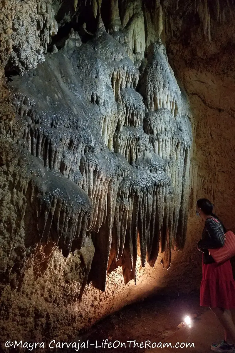 A woman standing next to a cave bacon formation