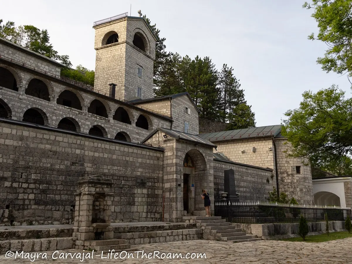 An old monastery in stone with arched windows and entrance and a tower