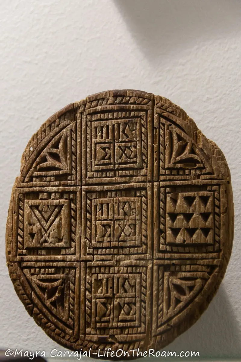 A round wooden seal with intricate carvings