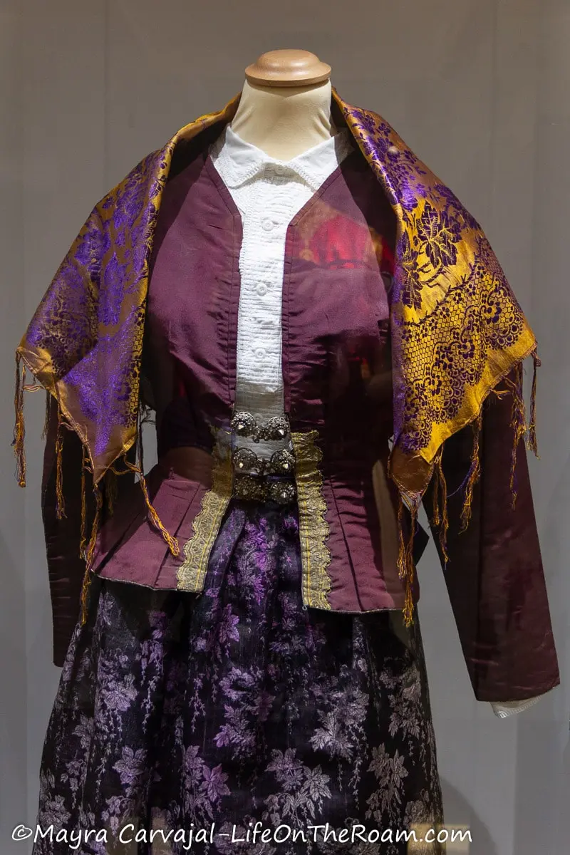 An elaborate traditional custome with a gold and purple  jacket and a patterned skirt