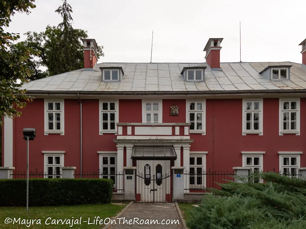 A 2-story large house painted in dark pink with rectangular windows with white frames and a white double door