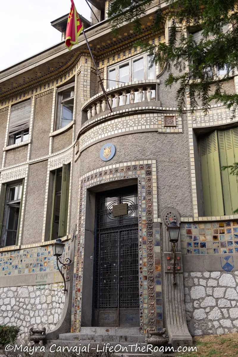 A double door entrance with a balcony on top framed with multicolour tiles