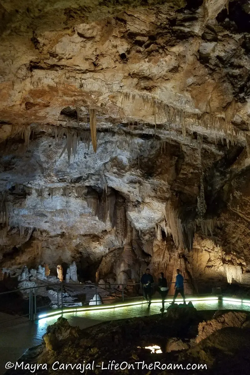 People walking on an illuminated platform inside a big cave