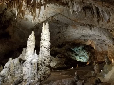 A cave with two big stalagmites on the left and small stalactites above