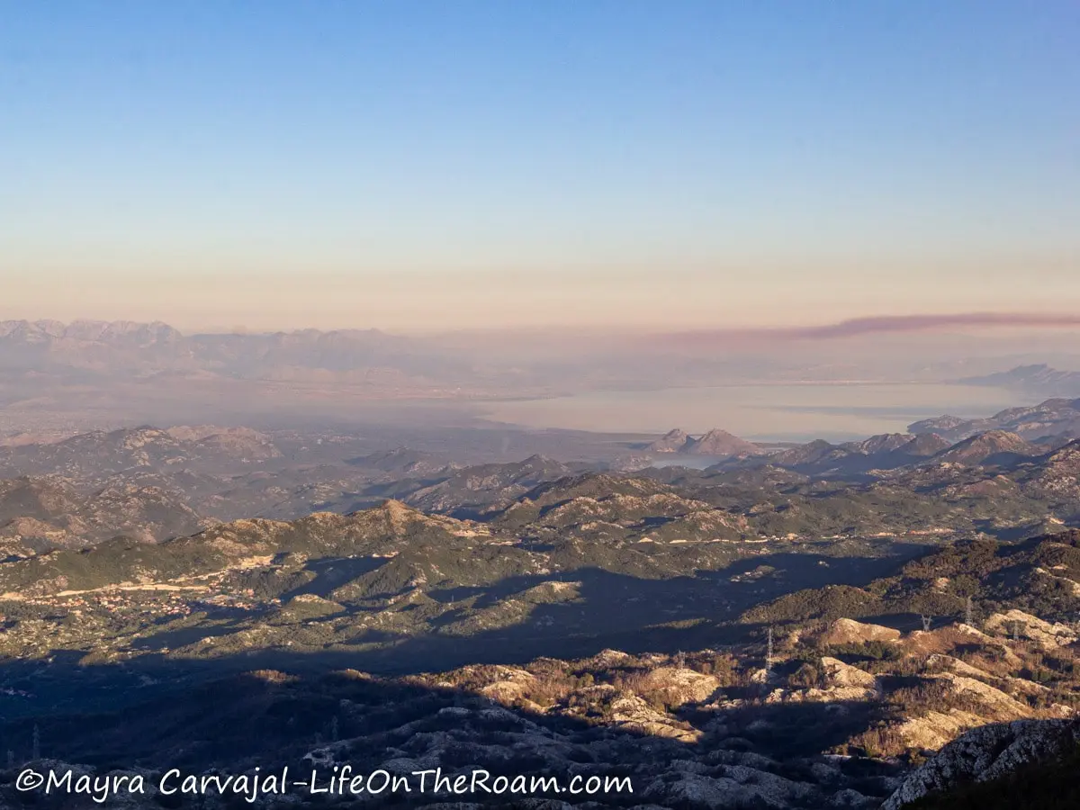 Aerial view of a mountain with a big lake in the distance, with sunset light