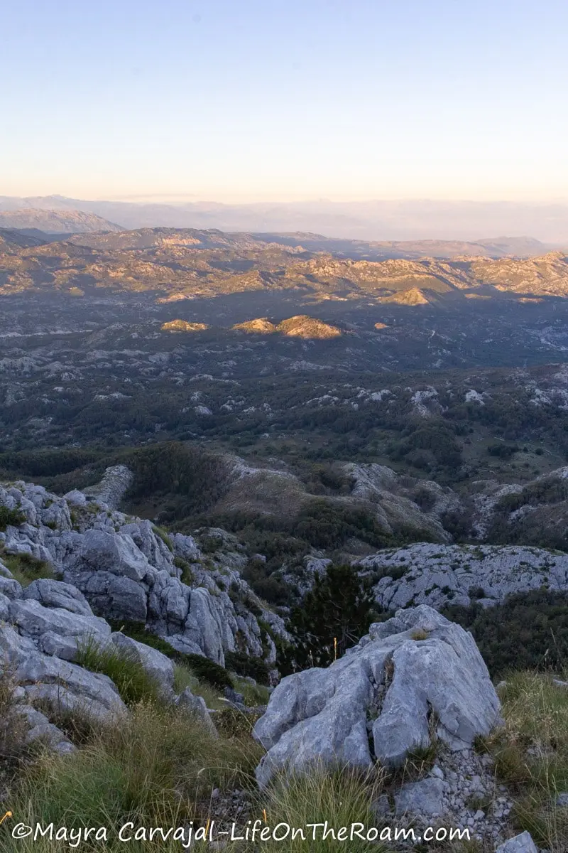 Extensive views of mountains with big light gray rocks in the foreground