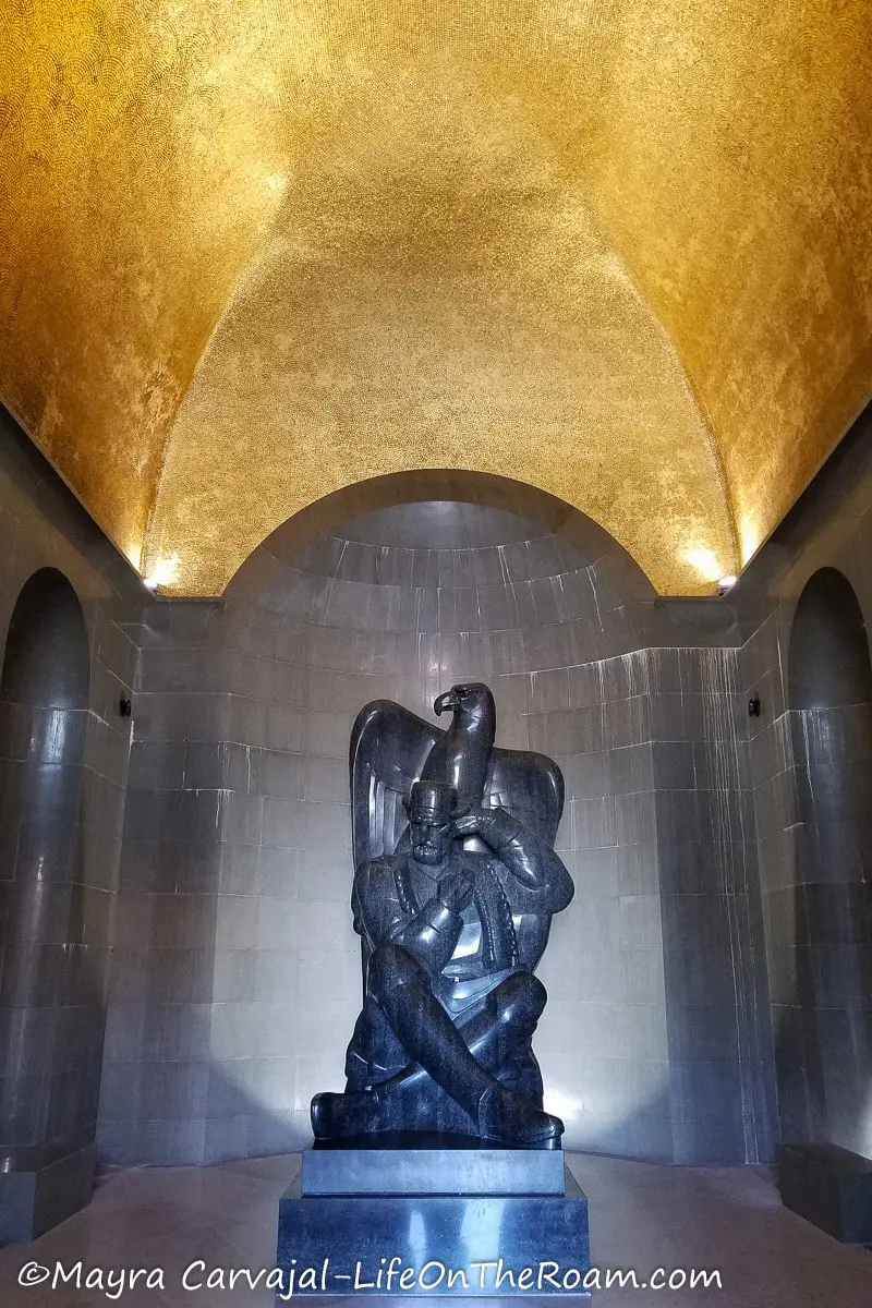 A black granite statue depicting a man and an eagle, under a dome covered with a golden mosaic