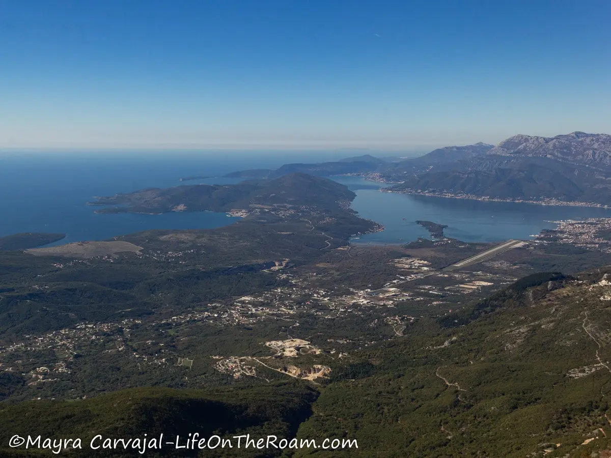 High view of a bay with fjord-like formations and the sea beyond.