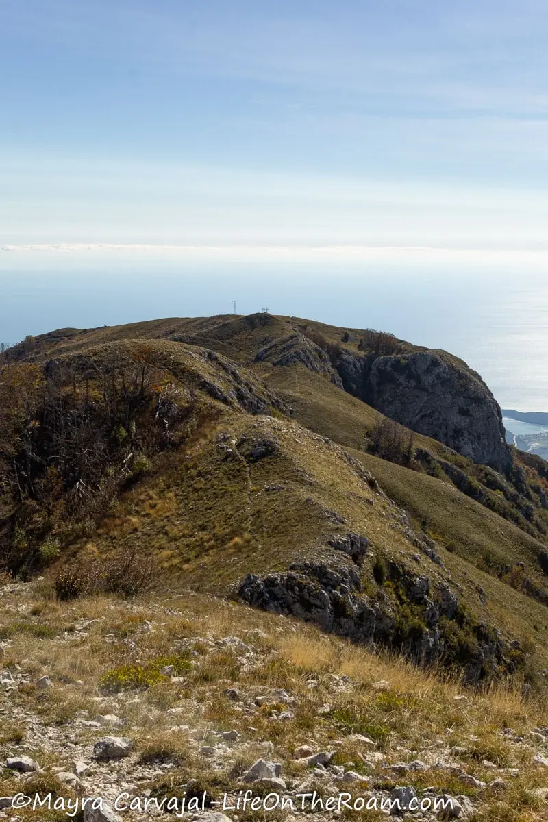 A trail along a bare mountain leading to a view of the coast