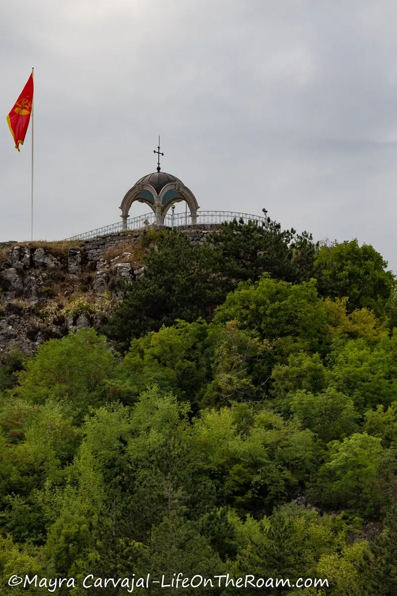 A gazebo-like structure at the top of a verdant hill