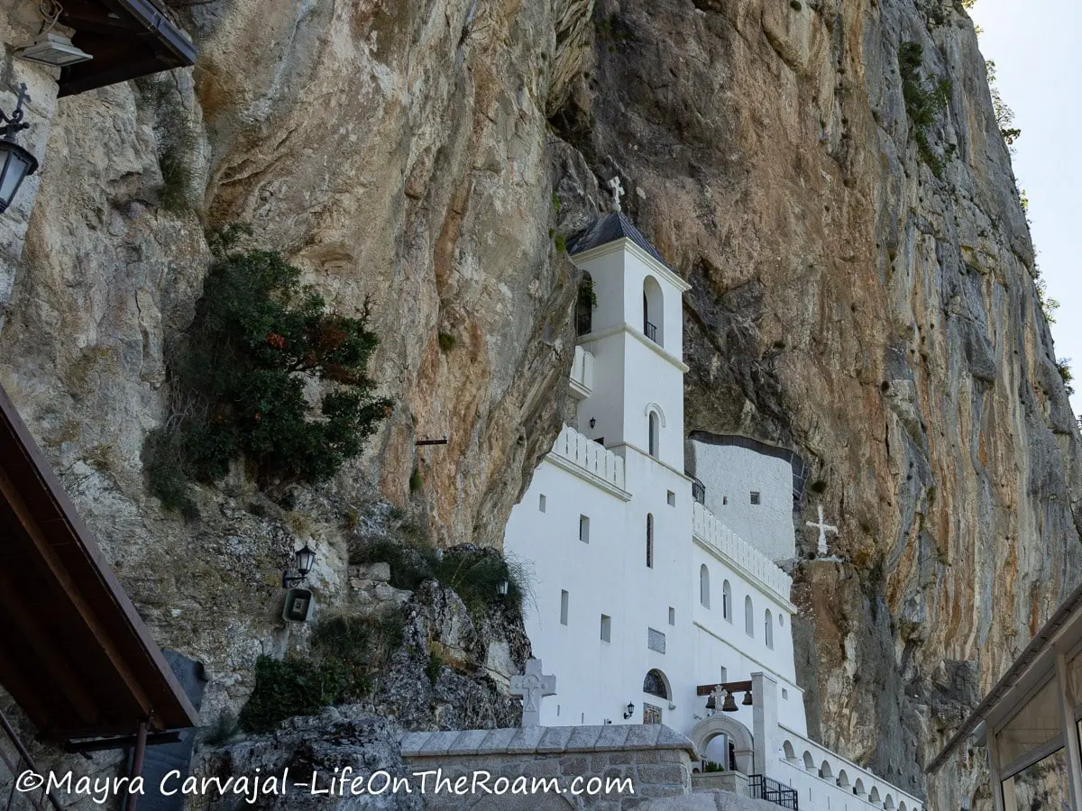 A white building with arched windows against a tall cliff