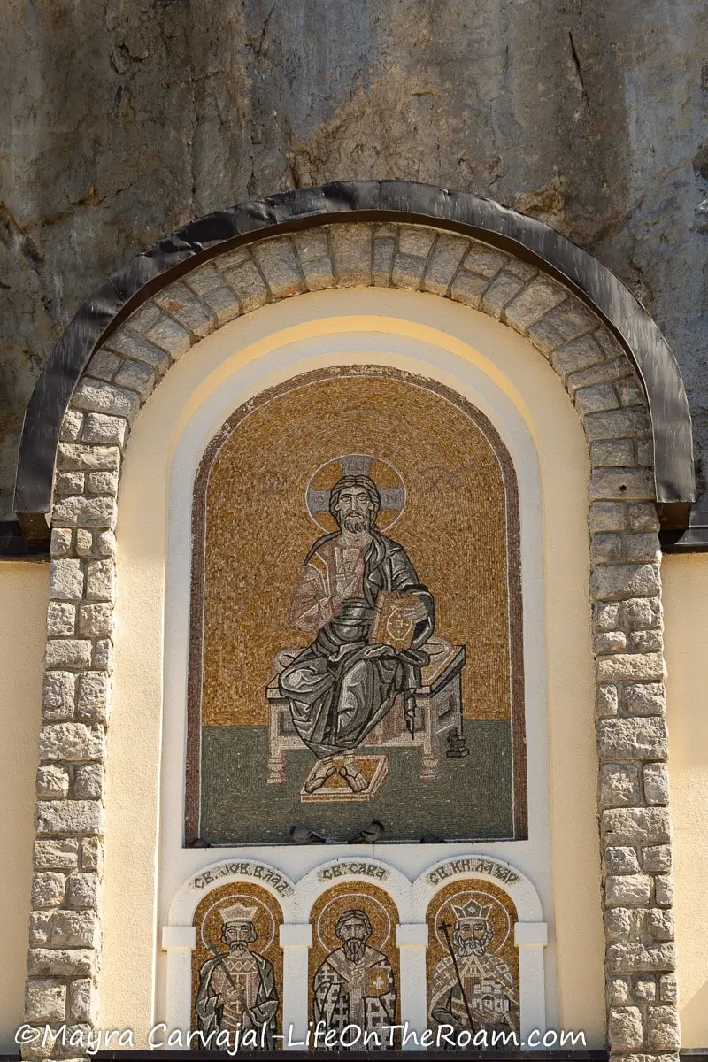 A mosaic on an arch of a building depicting  a saint sitting down