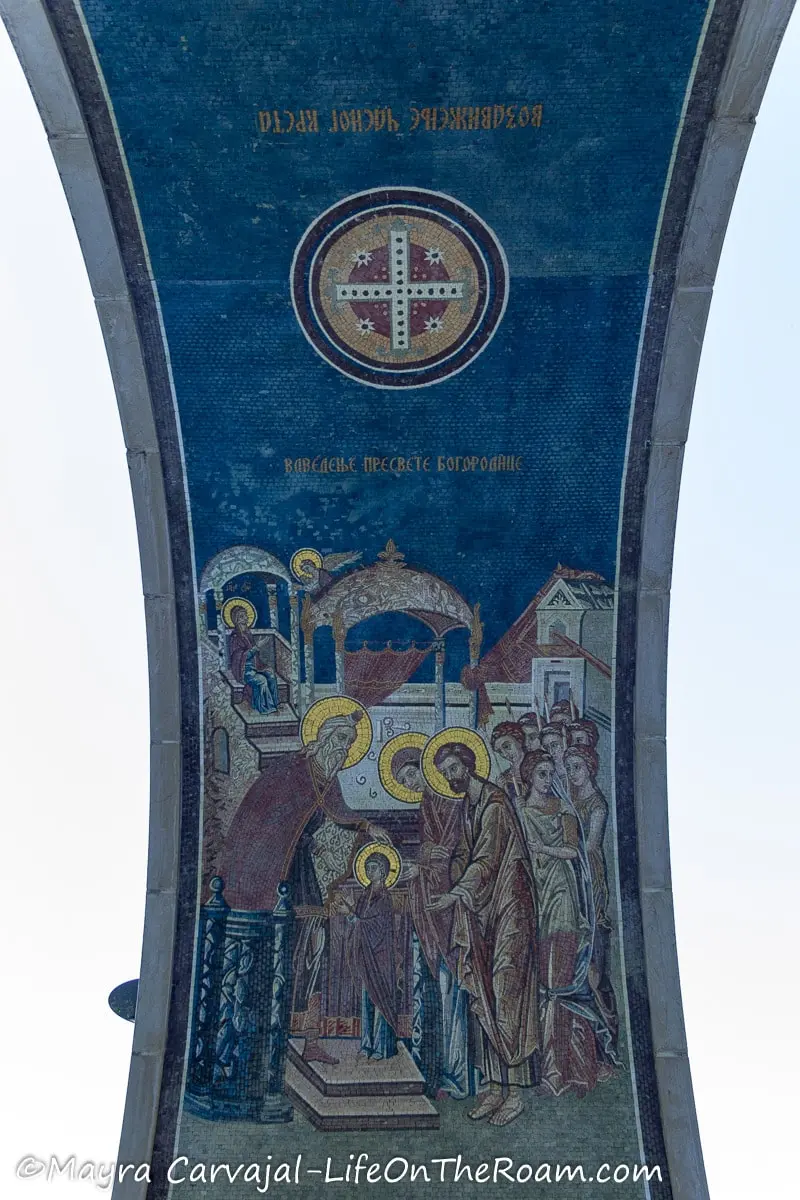 A mosaic under an arch depicting saints baptizing a child