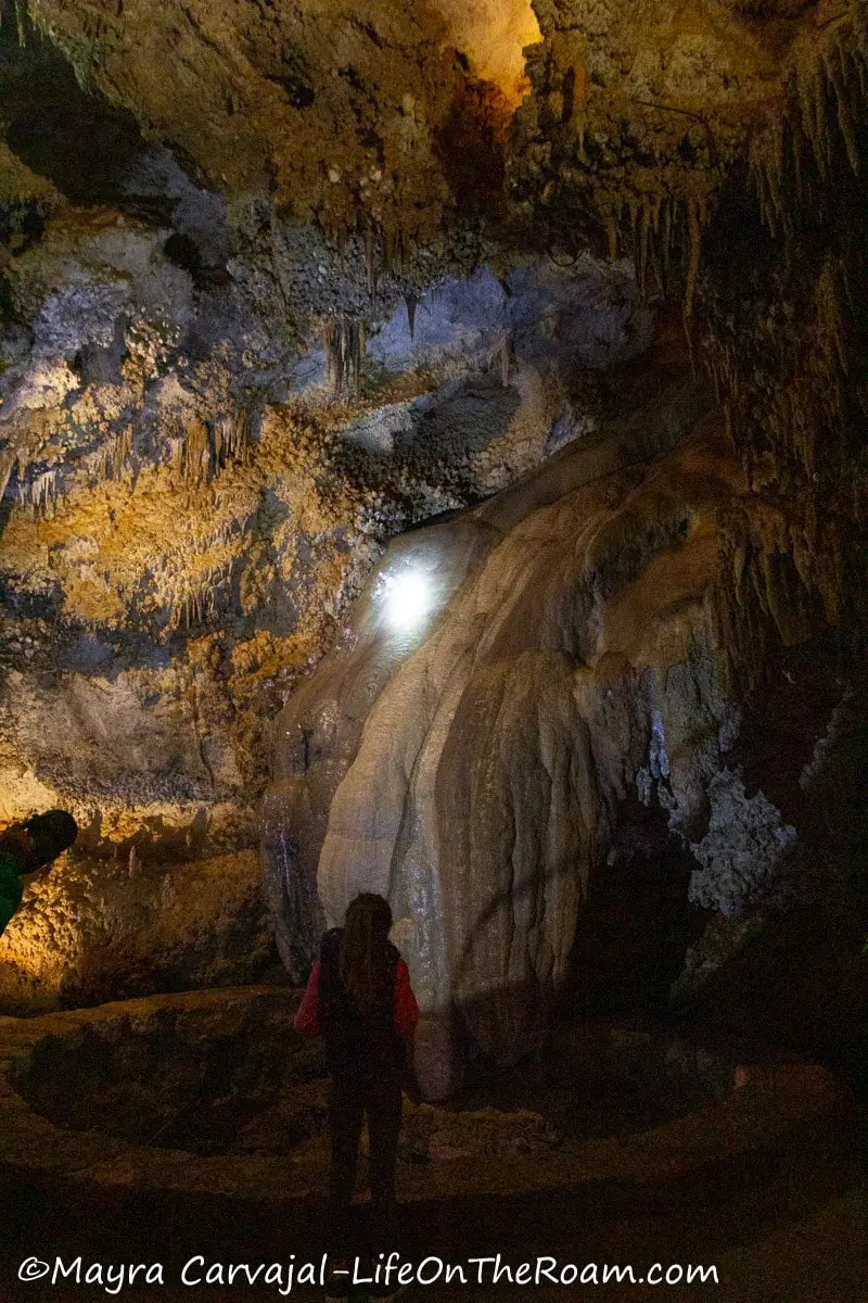 A woman illuminating cave formations and stalactites with a flashlight