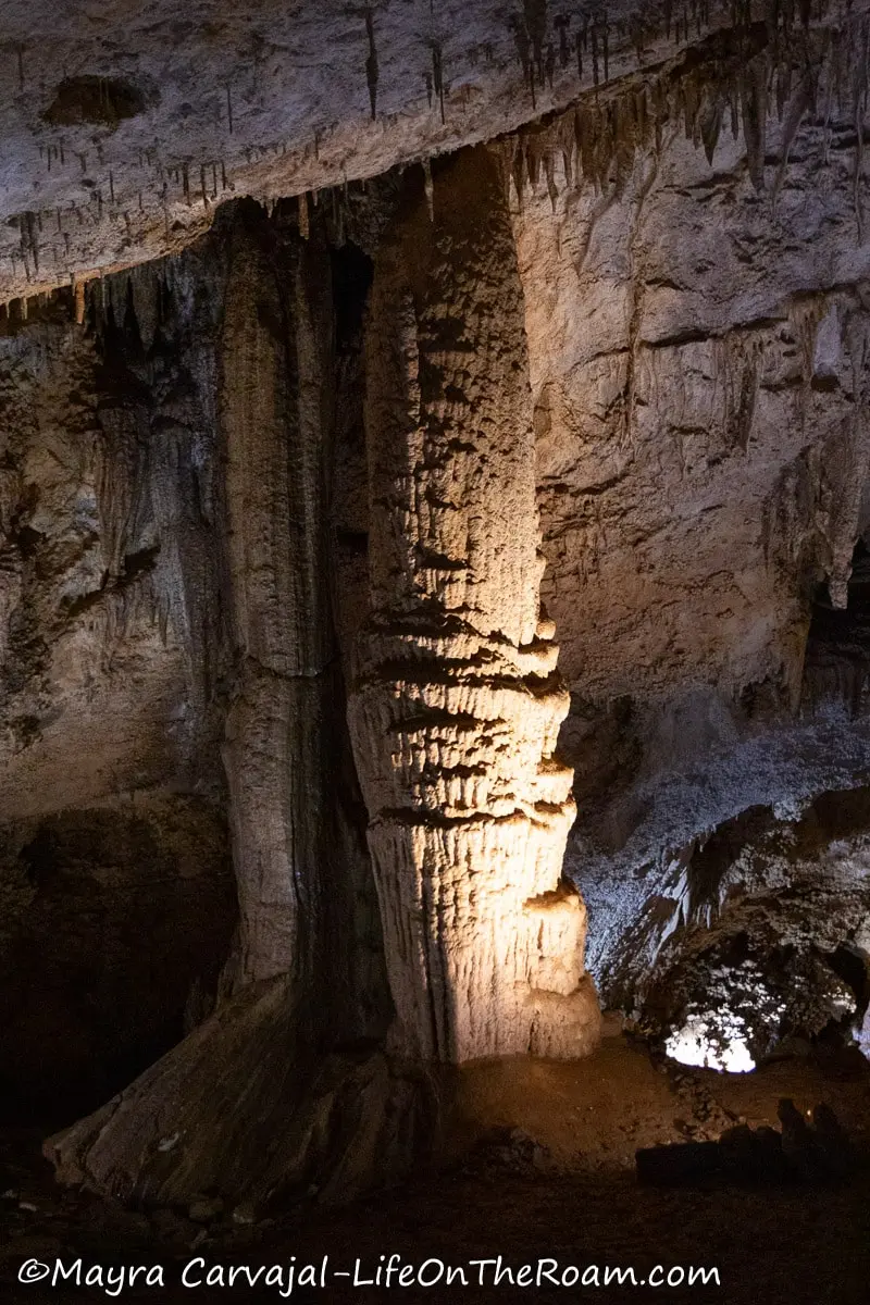 A column of calcium carbonate inside a cave highlighted by  a spotlight