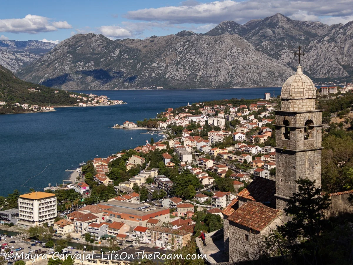 View of a coastal town with mountains in the background and a belfry in the foreground