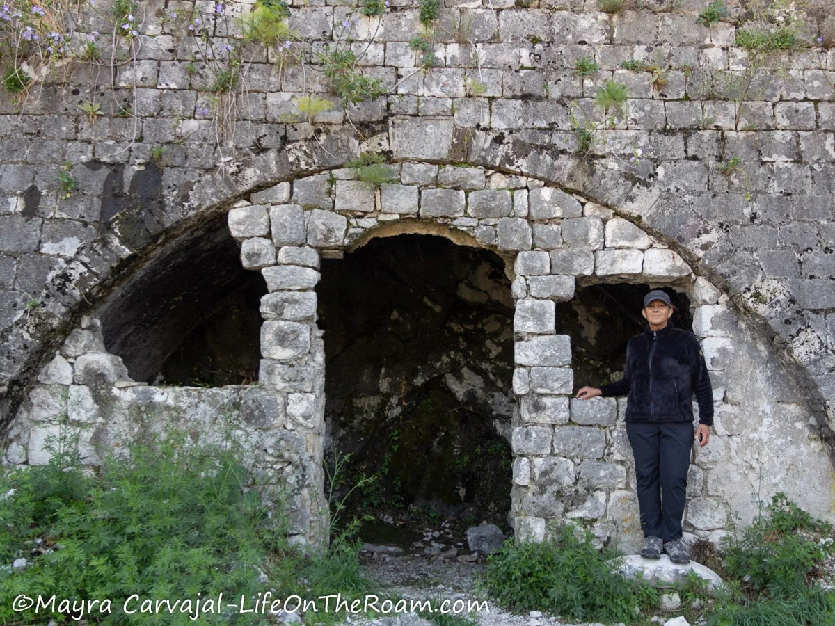 Mayra standing next to an opening close to a fortification in ruins