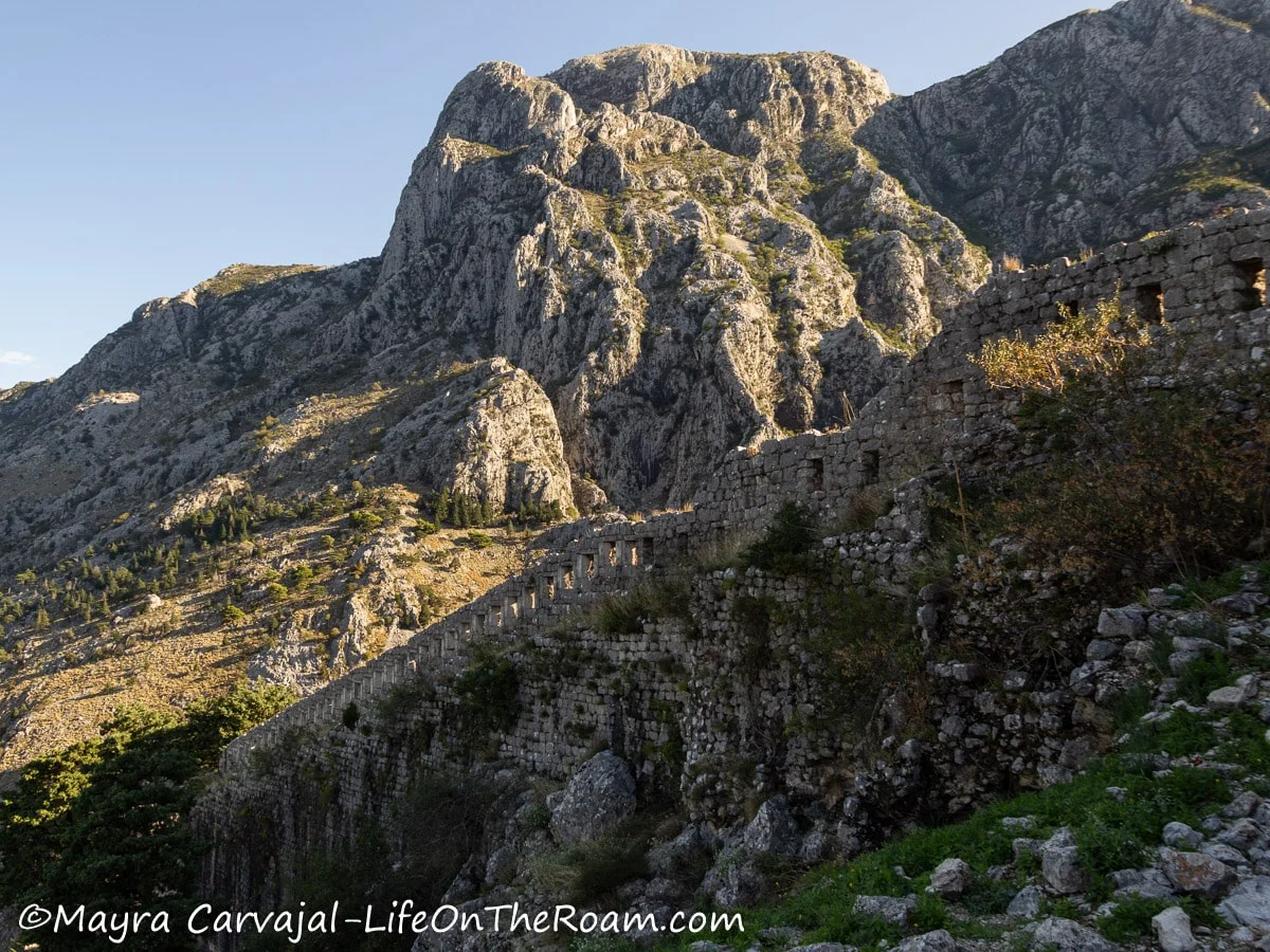 View of the rugged landscape of a hill beyond the remains of a stone military wall