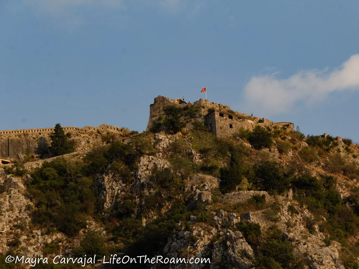 An old fortress at the top of a hill with the Montenegrin flag