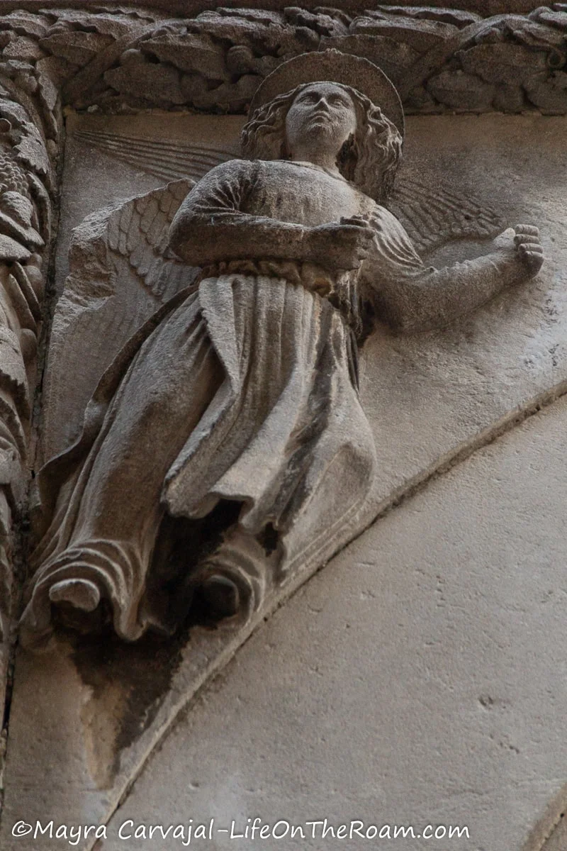 A stone angel on the corner of a tympanum