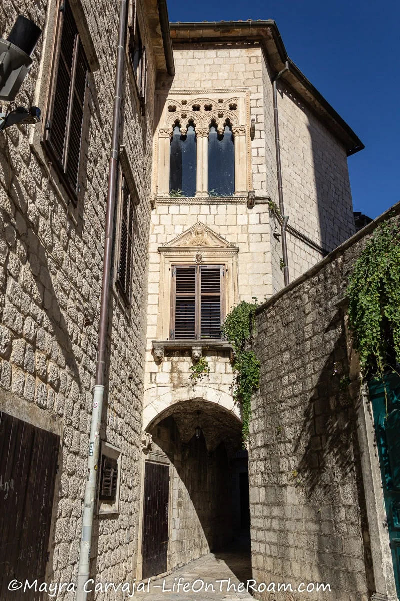 Entrance to a covered narrow alleyway with two windows in the upper section