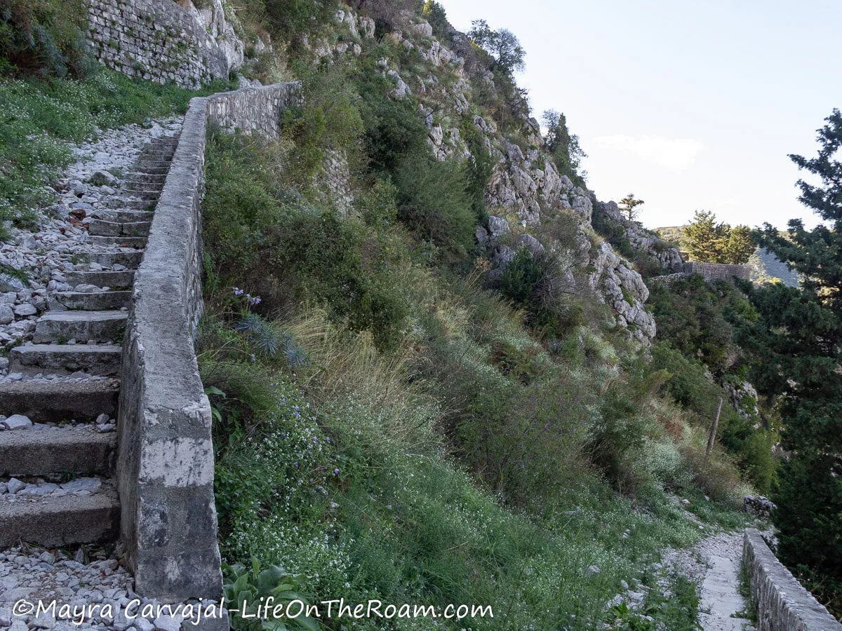 Narrow and worn stone steps along a stone wall built up in a mountain