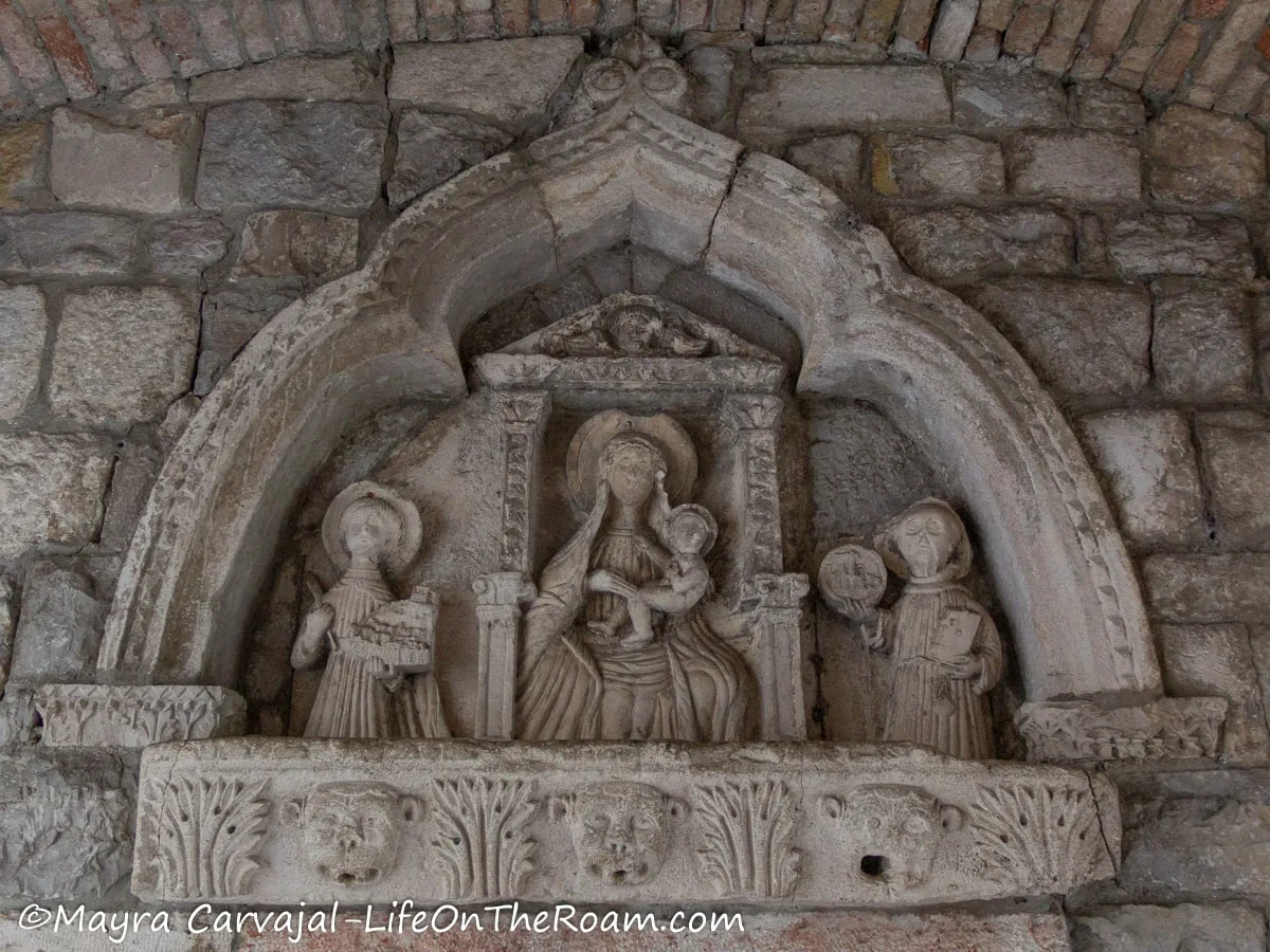 Close up of an altar with Madonna and Child on a throne surrounded by two church saints