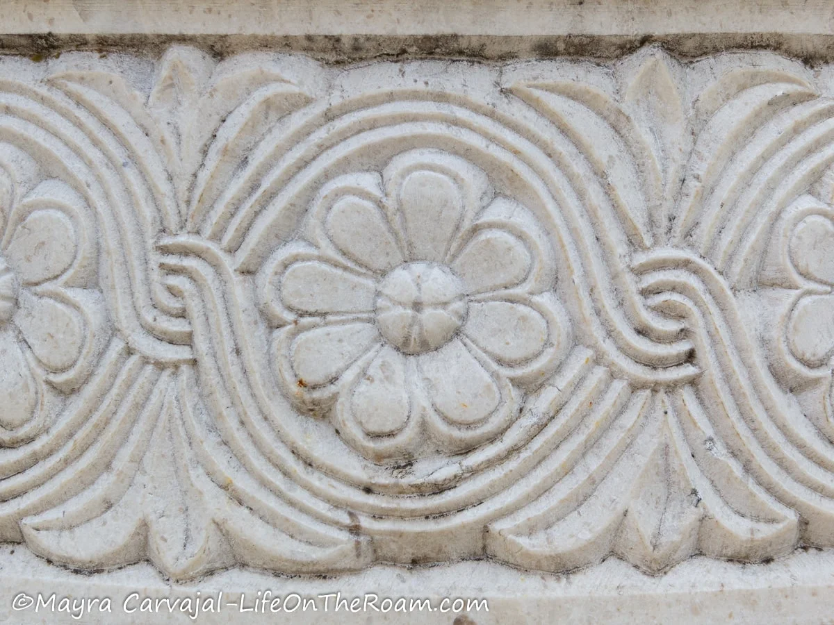 A pattern carved in marble featuring floral motifs and a curved geometric pattern