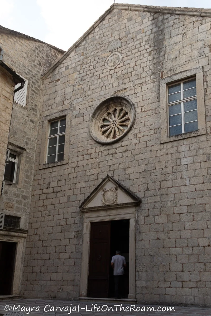 A small stone church with a door entrance crowned by a pediment and a rose window above