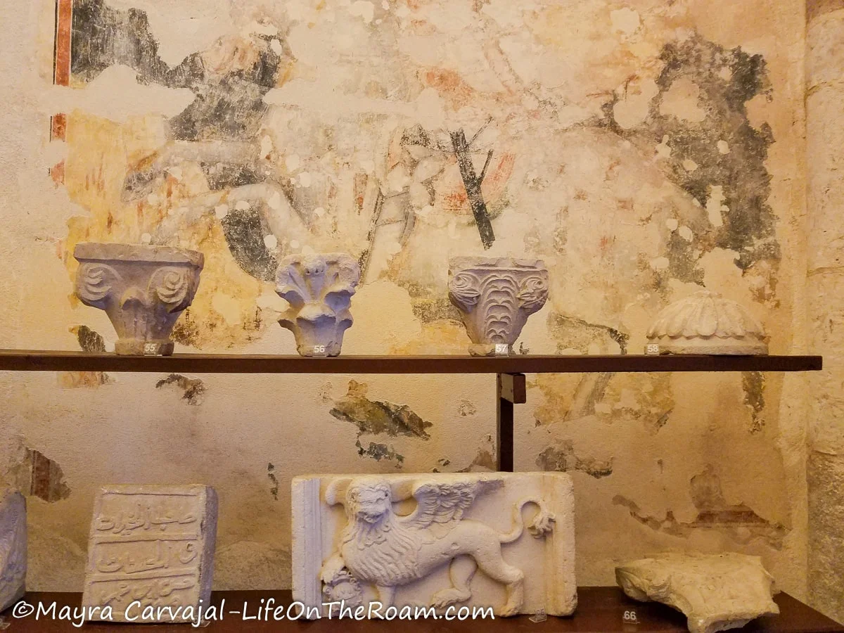 A display of artifacts with an ancient fresco on the back wall