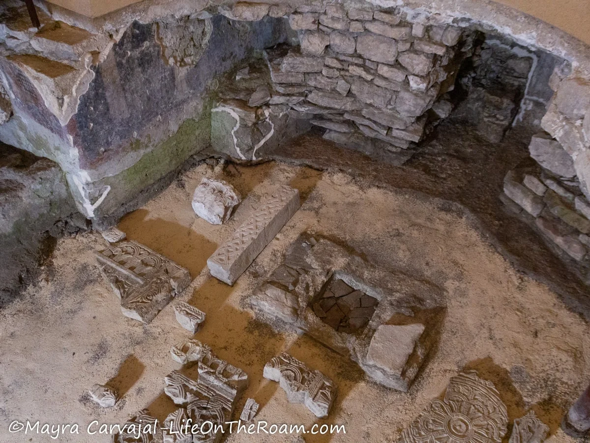 Fragments of artifacts displayed on the underground of a church with walls and fragments of frescoes exposed