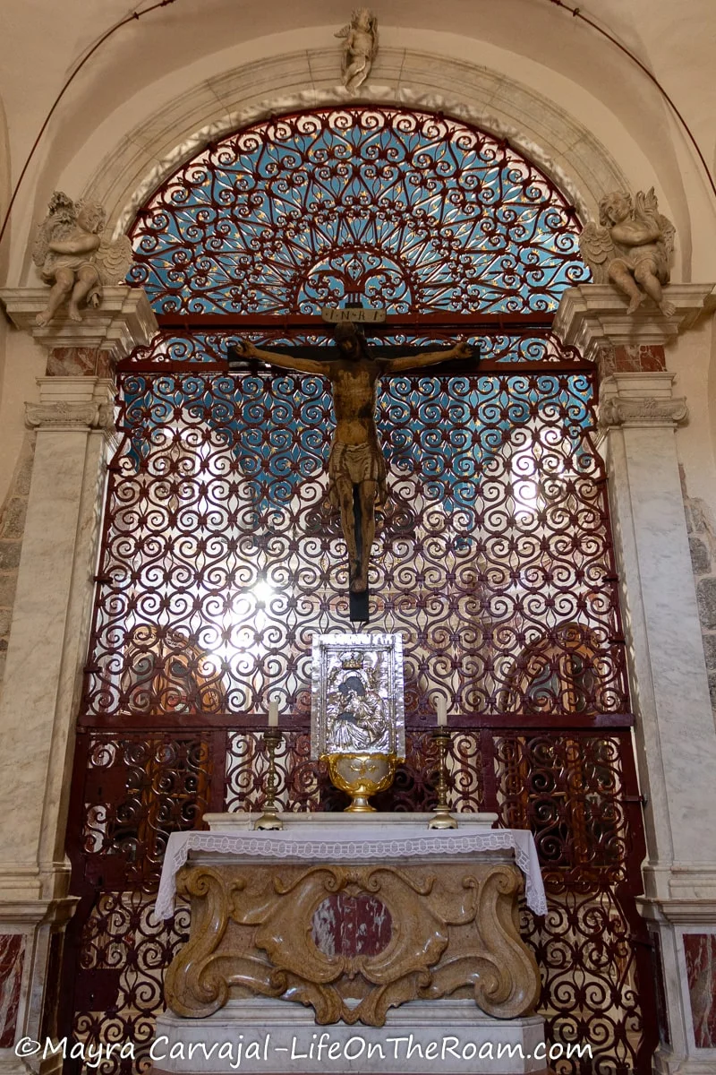 A highly detailed huge iron gate with a crucifix and an altar in front
