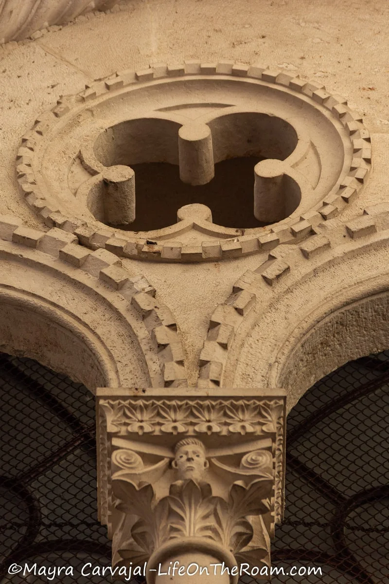 Close up of a capital and a quatrefoil in a window