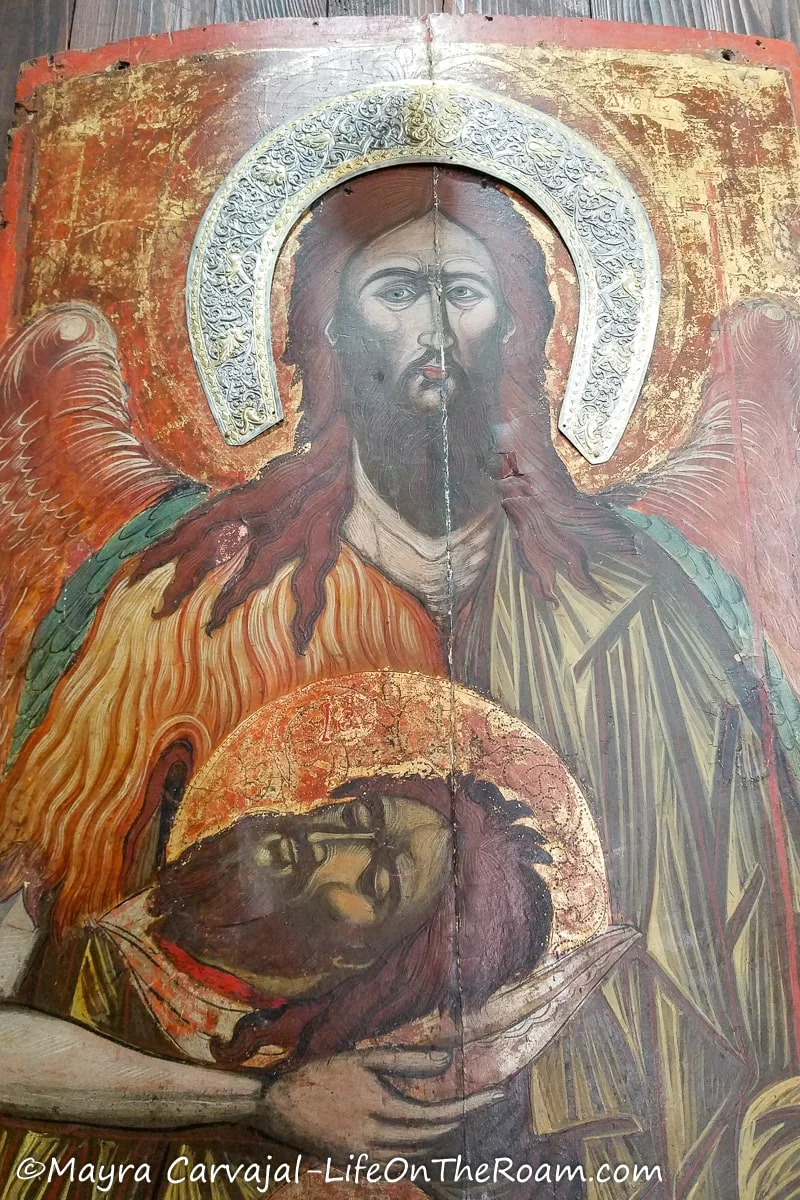An old religious painting in bright colours on a piece of wood with some riza