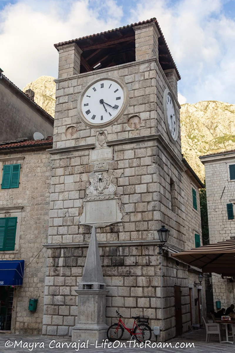 A stone tower with a big clock on the upper part