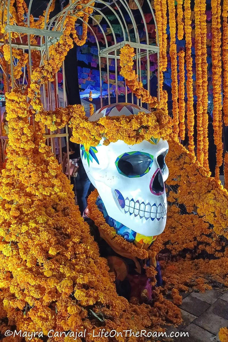 A giant painted skull surrounded by marigold-like flowers