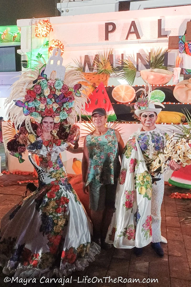 Mayra posing with a man and a woman dressed as Catrina and Catrin with elaborate costumes and make up