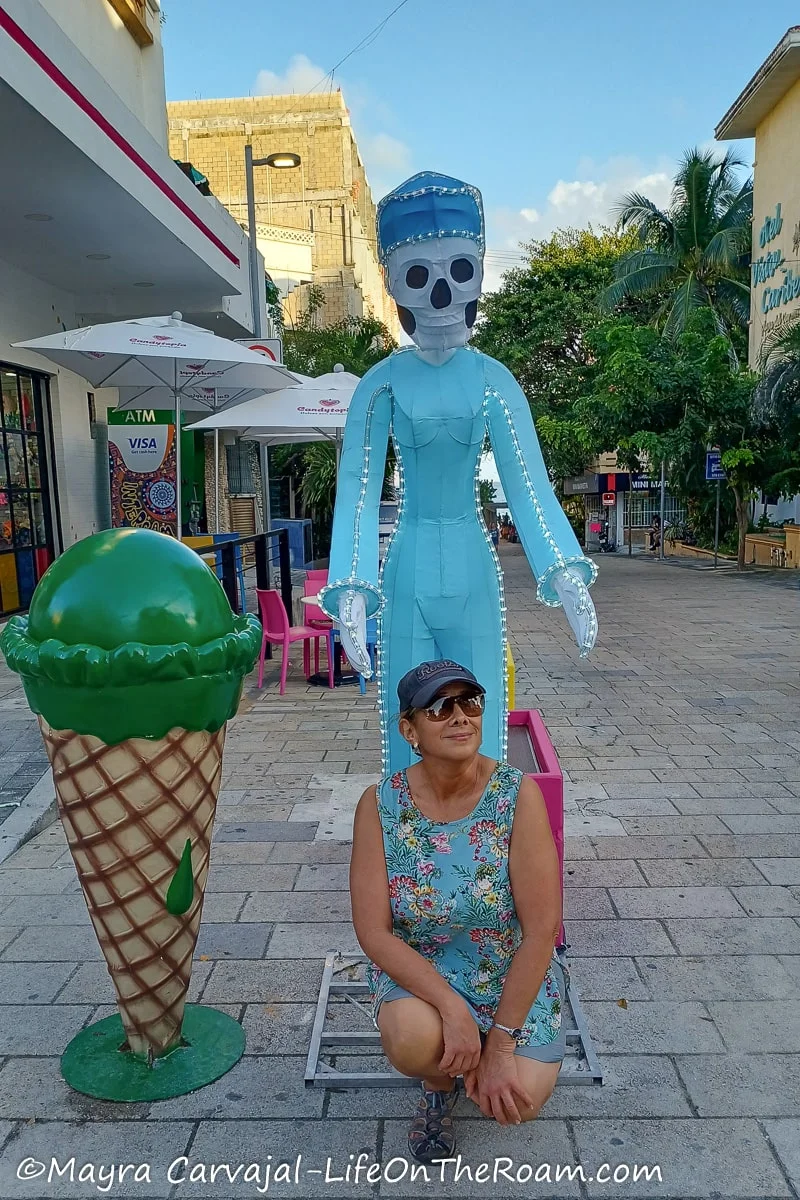 Mayra kneeling next to big skeleton figure dressed as a medical personnel