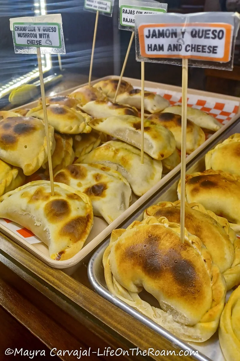 Baked empanadas on a tray behind a counter