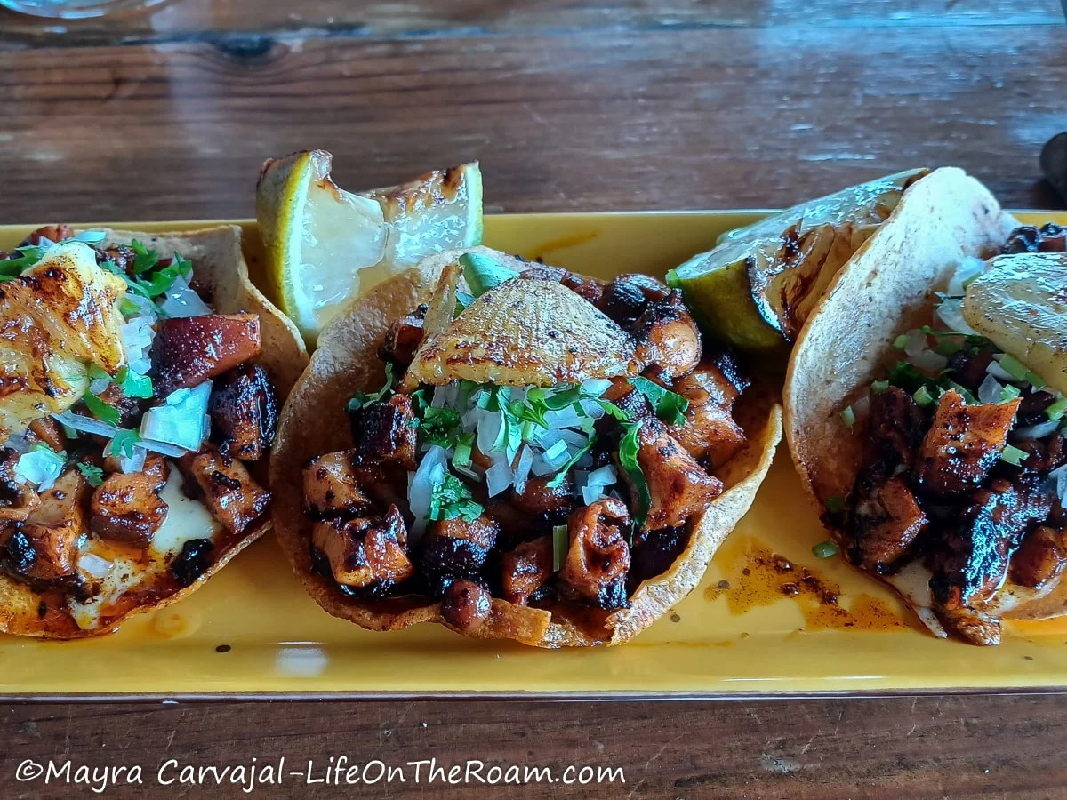 Three octopus tostadas served on a plate with grilled pineapple on top