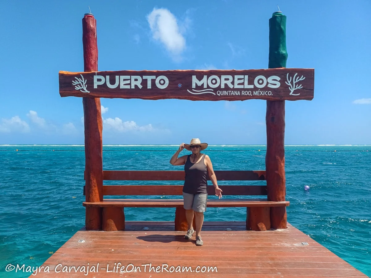 Mayra standing at the end of a pier under a sign that reads "Puerto Morelos"