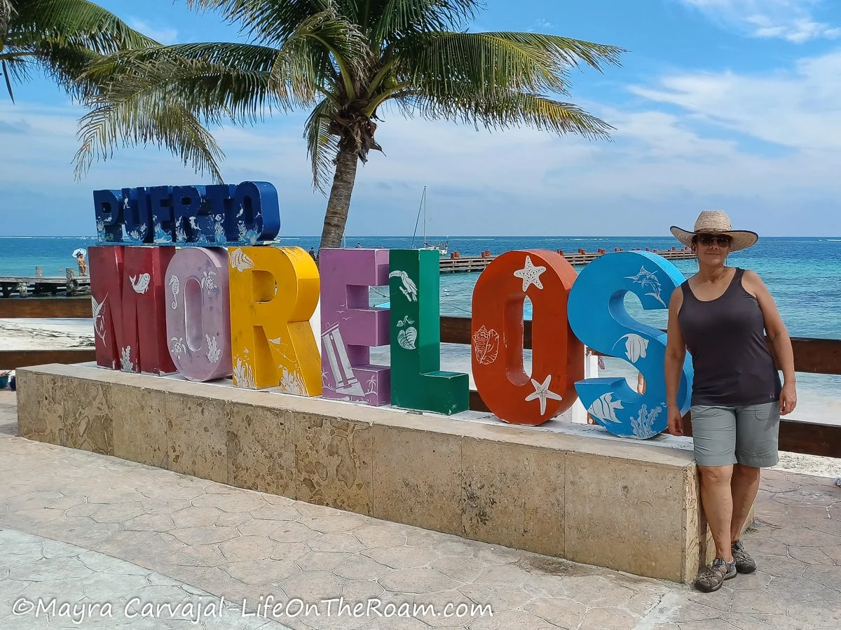 Mayra standing next to the Puerto Morelos letters